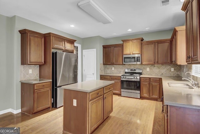 kitchen with a kitchen island, a sink, visible vents, light wood-style floors, and appliances with stainless steel finishes