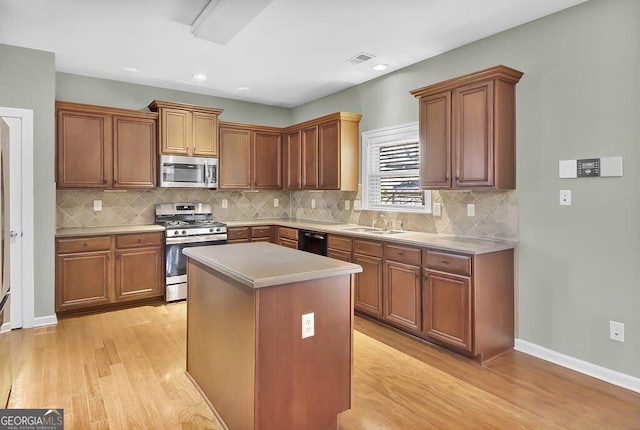 kitchen with stainless steel appliances, light countertops, a sink, and light wood-style flooring