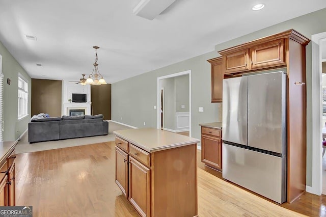 kitchen featuring light wood-type flooring, a fireplace, light countertops, and freestanding refrigerator