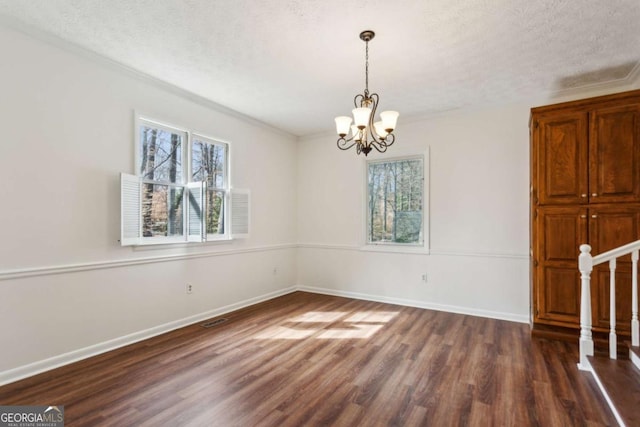 unfurnished dining area featuring a textured ceiling, a notable chandelier, visible vents, baseboards, and dark wood-style floors