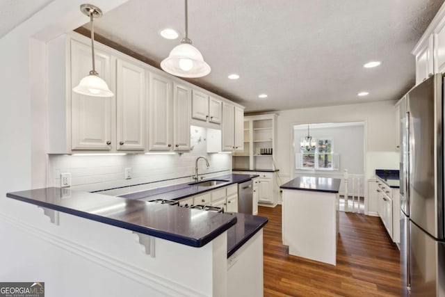 kitchen featuring dark wood-style flooring, dark countertops, appliances with stainless steel finishes, white cabinets, and a sink