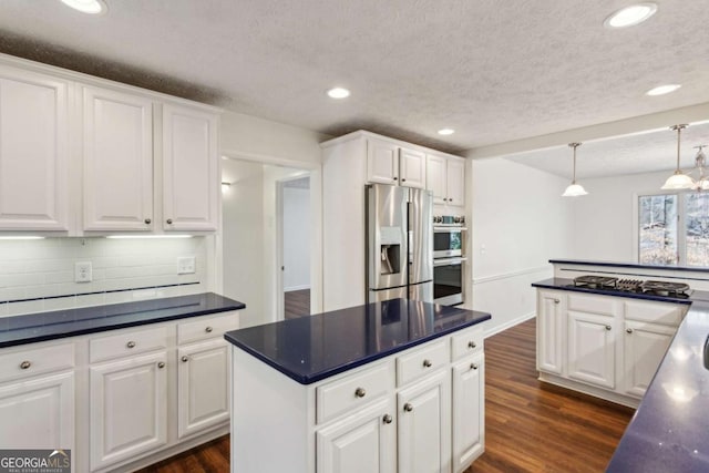 kitchen with appliances with stainless steel finishes, dark countertops, and dark wood-type flooring