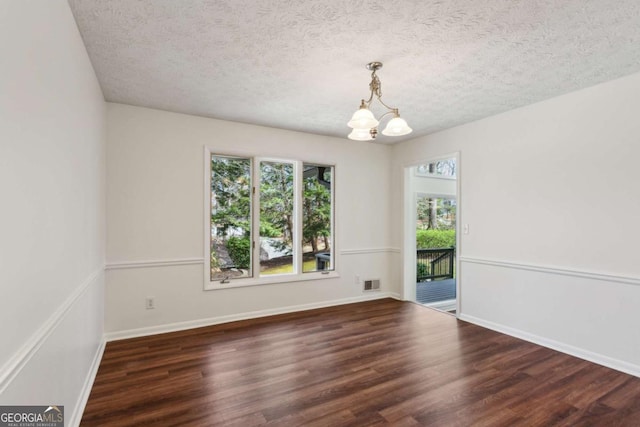 unfurnished room featuring visible vents, a textured ceiling, an inviting chandelier, and wood finished floors