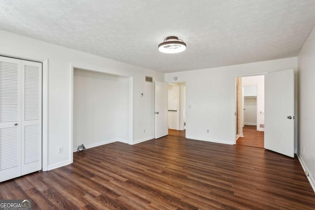 unfurnished bedroom with baseboards, visible vents, wood finished floors, a textured ceiling, and a closet