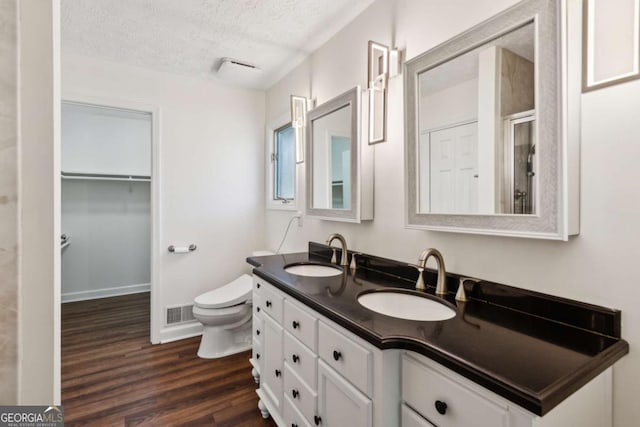 full bathroom featuring a sink, a textured ceiling, toilet, and wood finished floors