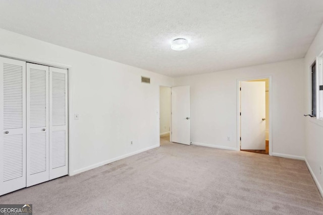 unfurnished bedroom with carpet floors, a closet, visible vents, a textured ceiling, and baseboards