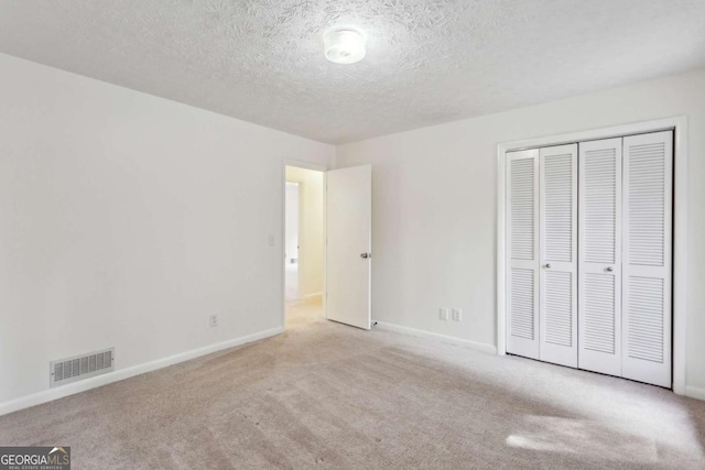 unfurnished bedroom with baseboards, carpet, visible vents, and a closet