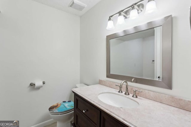 half bath featuring visible vents, vanity, and toilet