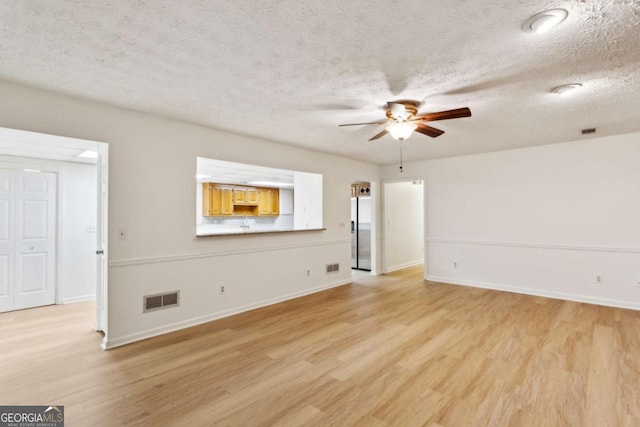 empty room with visible vents, ceiling fan, light wood-style flooring, and a textured ceiling