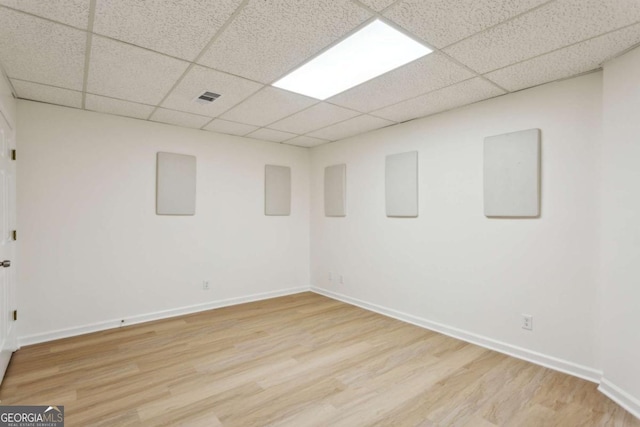 unfurnished room featuring a paneled ceiling, baseboards, visible vents, and wood finished floors