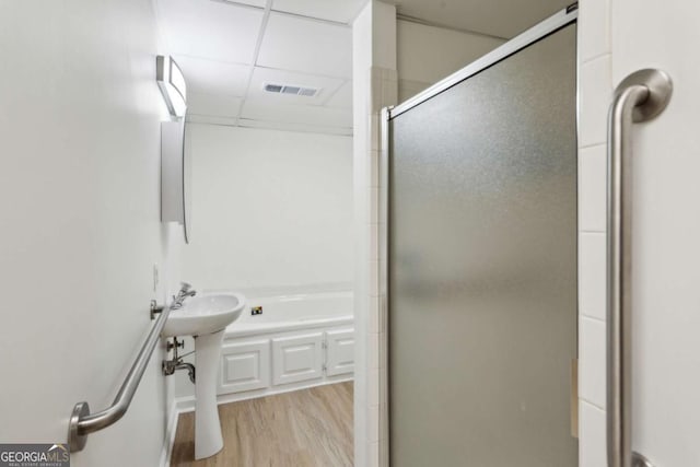 bathroom with a tub to relax in, visible vents, a drop ceiling, wood finished floors, and a shower stall