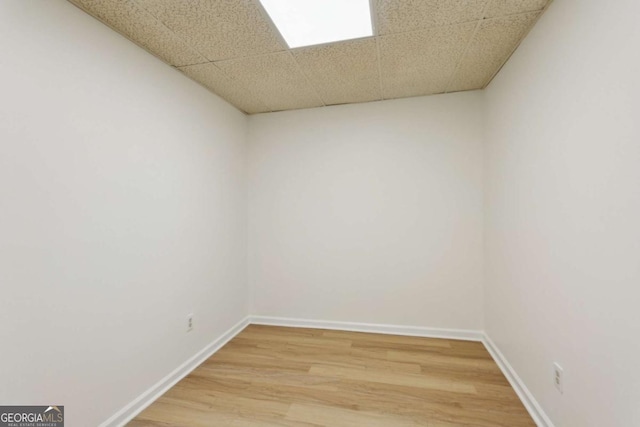 spare room featuring light wood-style floors, a paneled ceiling, and baseboards