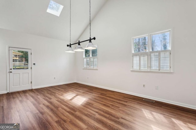 unfurnished dining area with a skylight, visible vents, wood finished floors, high vaulted ceiling, and baseboards