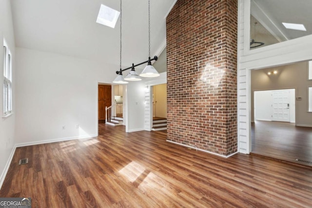 unfurnished living room with high vaulted ceiling, a skylight, visible vents, and stairway