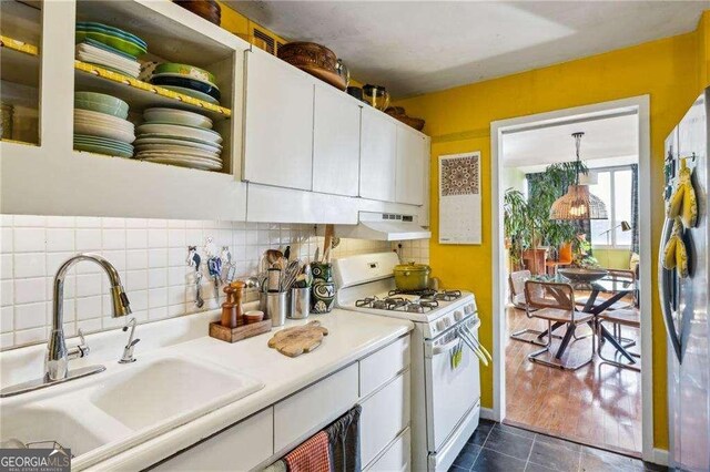 kitchen with freestanding refrigerator, white cabinetry, white range with gas cooktop, and a sink