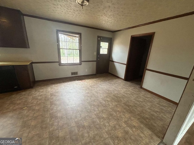 unfurnished dining area with visible vents, ornamental molding, a textured ceiling, baseboards, and tile patterned floors