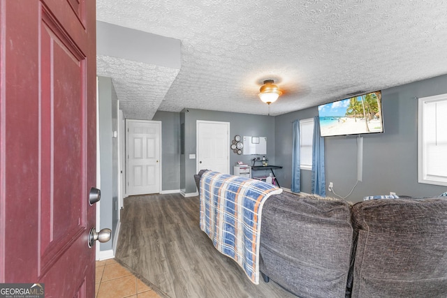 living room with a healthy amount of sunlight, baseboards, a textured ceiling, and tile patterned floors