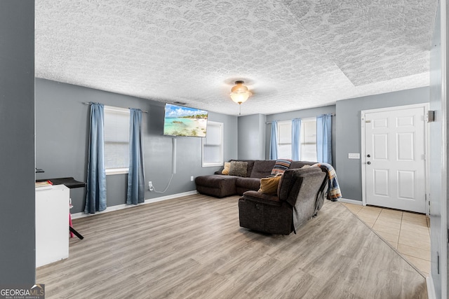 living room featuring a textured ceiling, baseboards, and wood finished floors