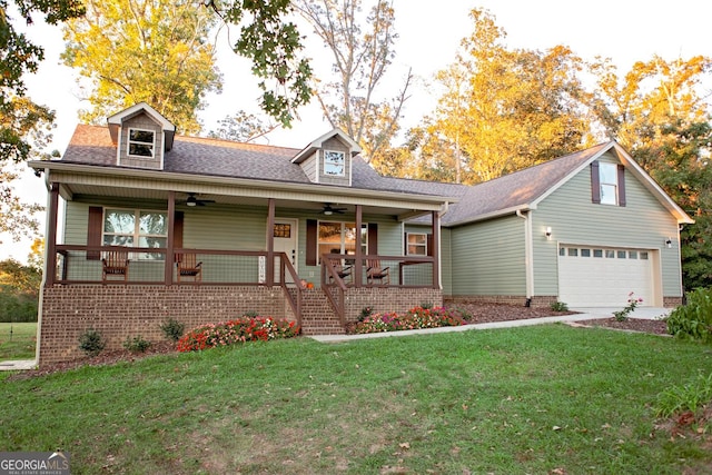 view of front of home featuring roof with shingles, a porch, a ceiling fan, a garage, and a front lawn