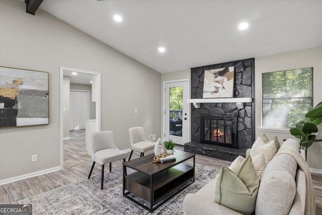 living area featuring lofted ceiling, a fireplace, wood finished floors, and baseboards