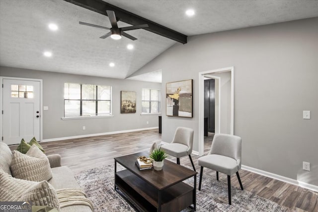 living area with vaulted ceiling with beams, wood finished floors, and baseboards