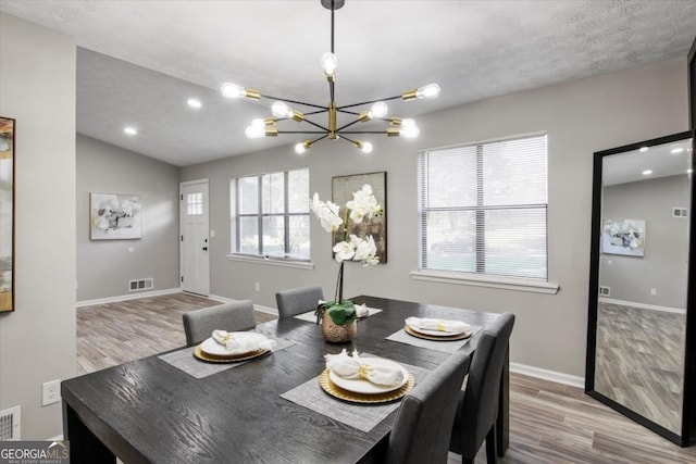 dining room featuring baseboards, wood finished floors, visible vents, and a notable chandelier