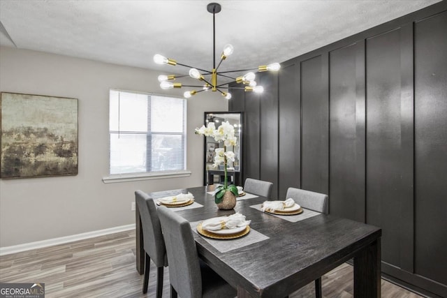 dining area with a notable chandelier, light wood-style flooring, and baseboards