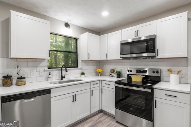 kitchen featuring a sink, white cabinetry, light countertops, appliances with stainless steel finishes, and tasteful backsplash