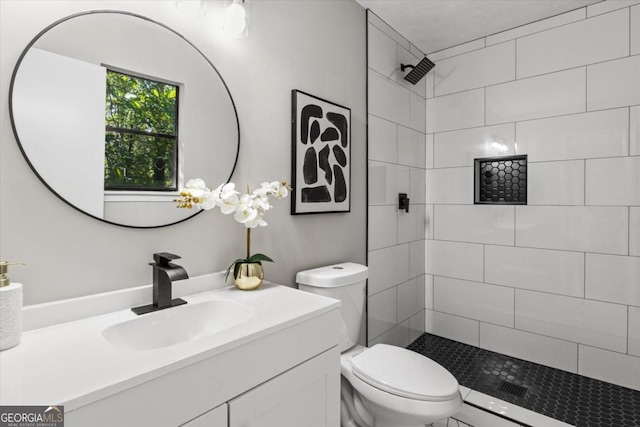 full bath with tiled shower, vanity, and toilet