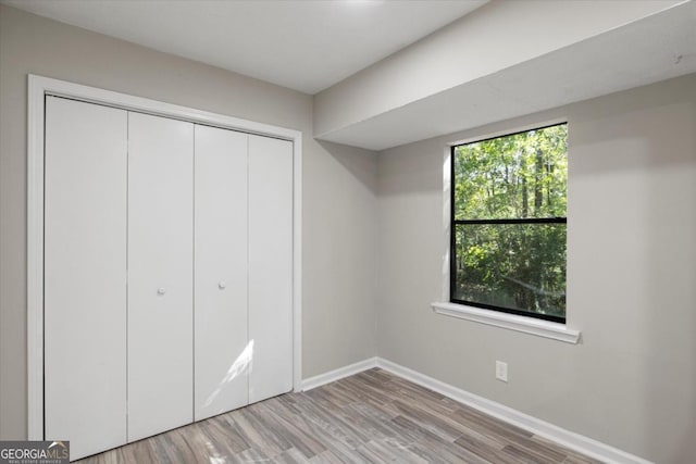 unfurnished bedroom with light wood finished floors, a closet, and baseboards