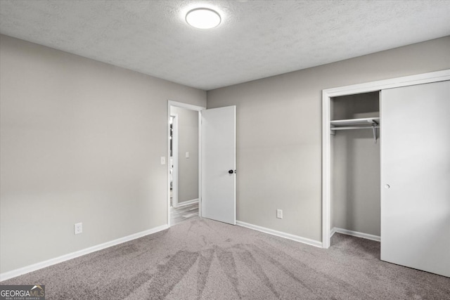 unfurnished bedroom with a textured ceiling, a closet, carpet, and baseboards