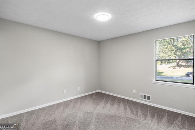 carpeted spare room with a textured ceiling, visible vents, and baseboards