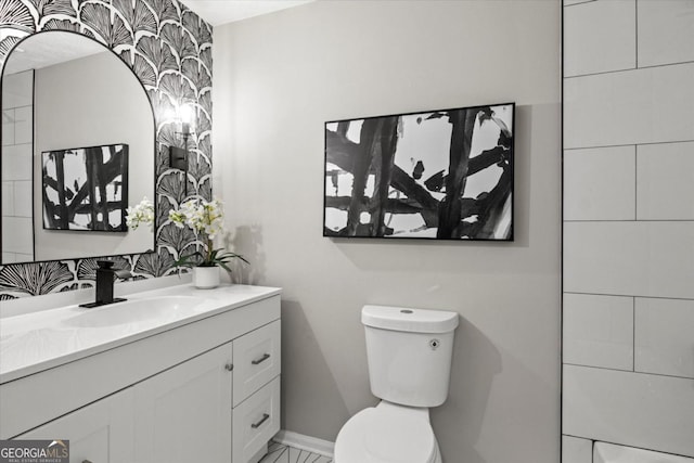 bathroom with baseboards, vanity, and toilet