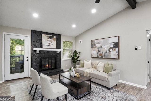 living room featuring lofted ceiling with beams, a healthy amount of sunlight, a fireplace, and wood finished floors