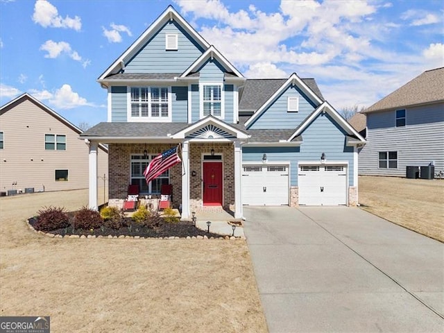 craftsman inspired home featuring brick siding, covered porch, an attached garage, a front yard, and driveway