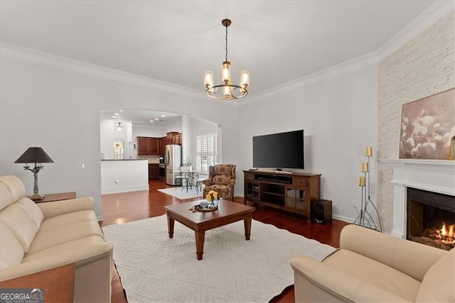 living room featuring arched walkways, a lit fireplace, ornamental molding, and dark wood-style flooring