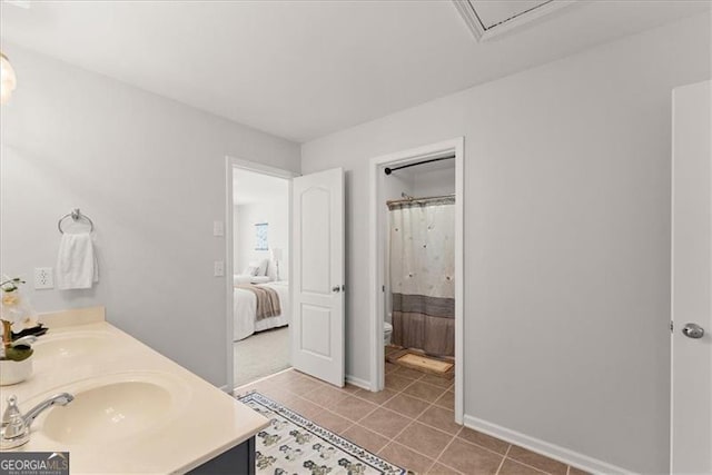 bathroom with double vanity, connected bathroom, toilet, tile patterned flooring, and a sink