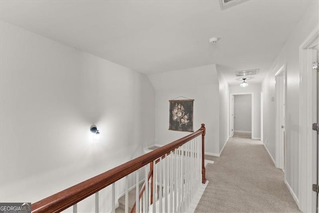 corridor featuring baseboards, light colored carpet, visible vents, and an upstairs landing