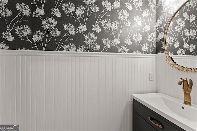 bathroom with a wainscoted wall, vanity, and wallpapered walls