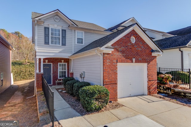 traditional home featuring a garage, driveway, fence, and brick siding