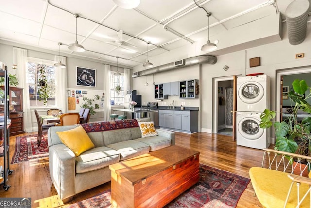 living room featuring stacked washer / dryer, visible vents, and dark wood finished floors