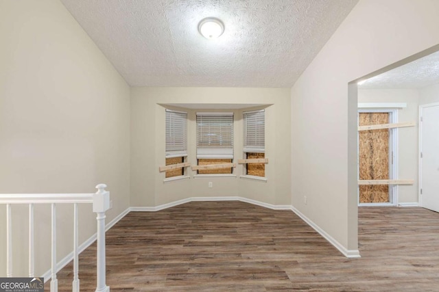 spare room featuring a textured ceiling, baseboards, and wood finished floors