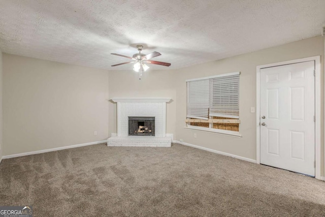 unfurnished living room featuring ceiling fan, a textured ceiling, a fireplace, baseboards, and carpet