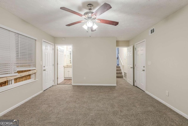 unfurnished bedroom with visible vents, light carpet, connected bathroom, a textured ceiling, and baseboards