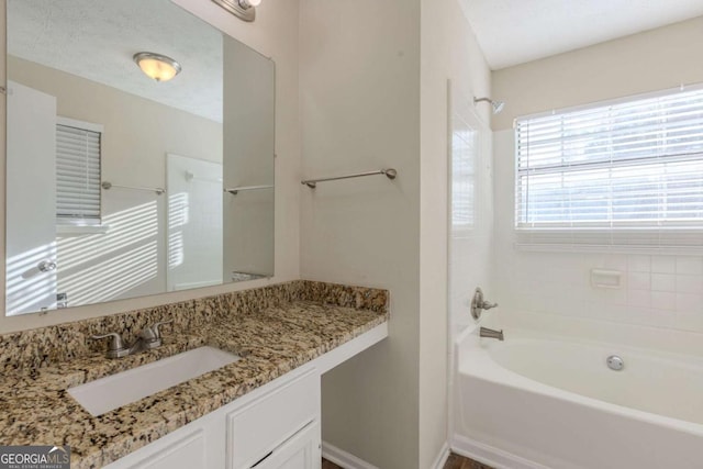 bathroom featuring a textured ceiling,  shower combination, vanity, and baseboards