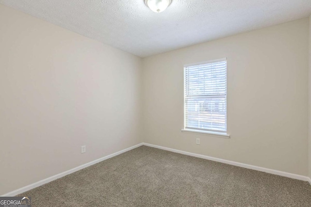 carpeted empty room featuring a textured ceiling and baseboards