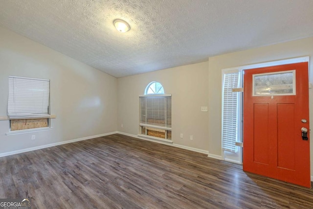 entrance foyer with a textured ceiling, baseboards, and dark wood-type flooring