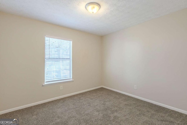 carpeted spare room featuring a textured ceiling and baseboards