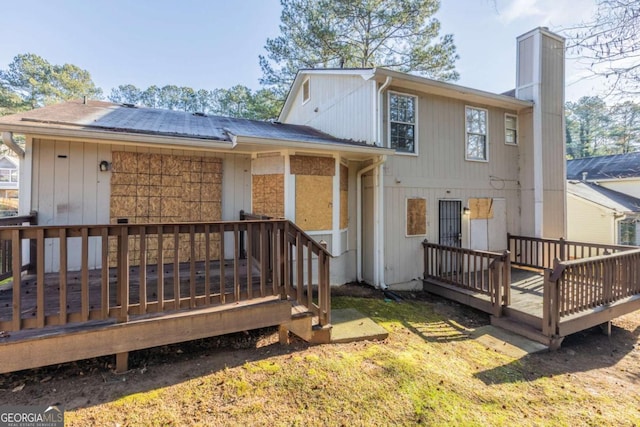 rear view of property featuring a chimney and a wooden deck