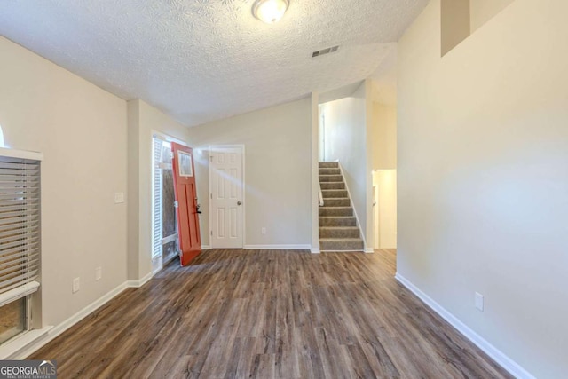 foyer entrance featuring lofted ceiling, stairway, wood finished floors, and visible vents